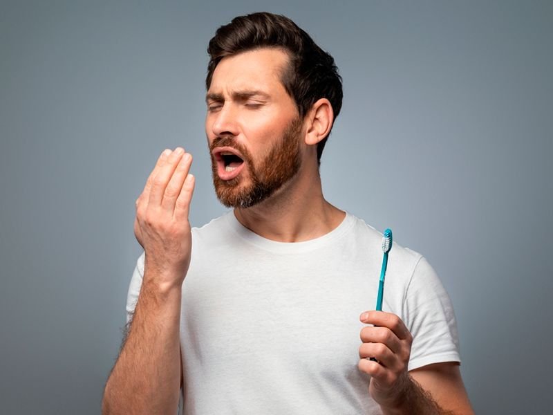 Man checking his breath after brushing, still concerned about persistent bad breath